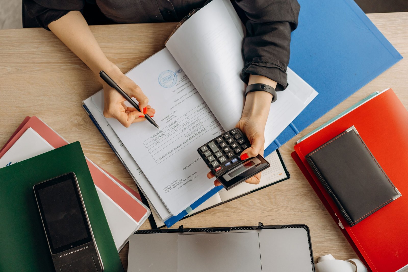 Small business owner calculating cash flow KPIs with a calculator and financial documents on a desk