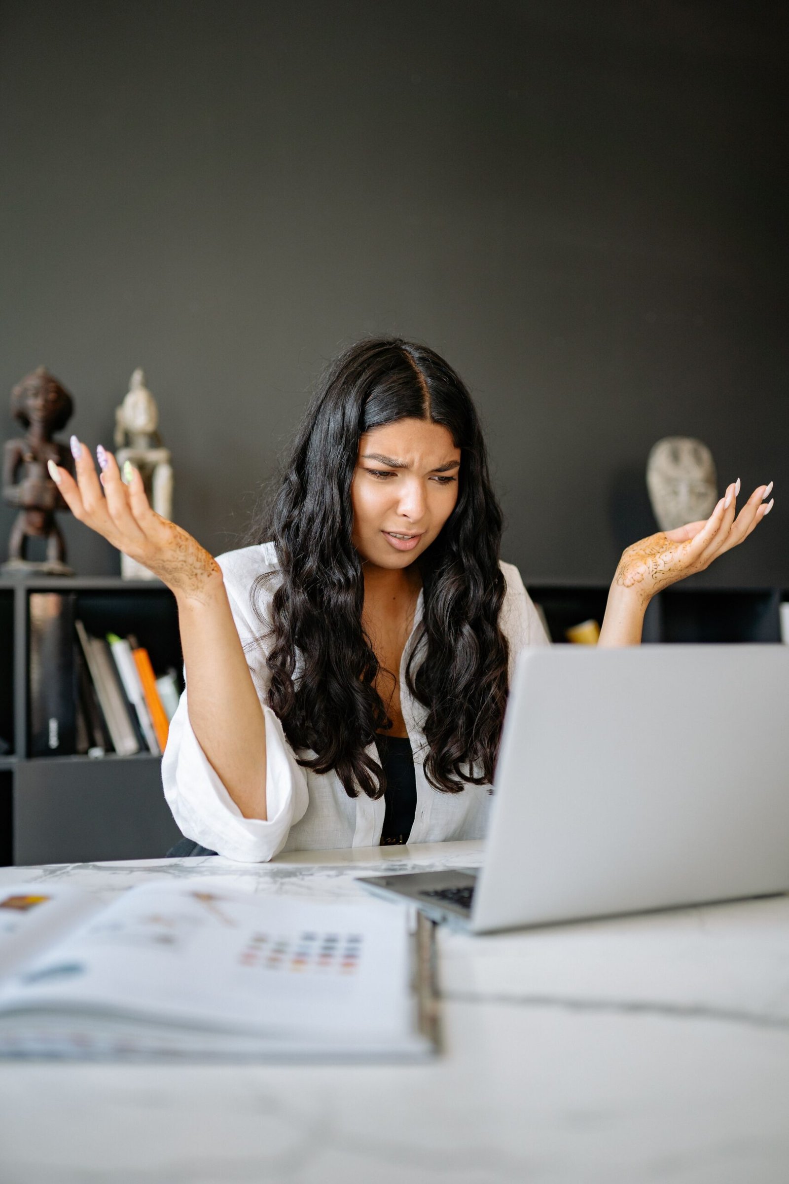 Frustrated businesswoman puzzled at her desk, representing common employee handbook mistakes