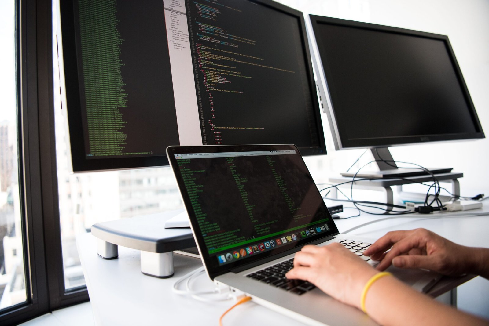 Person working at multiple computer monitors, representing a data backup strategy for a small business