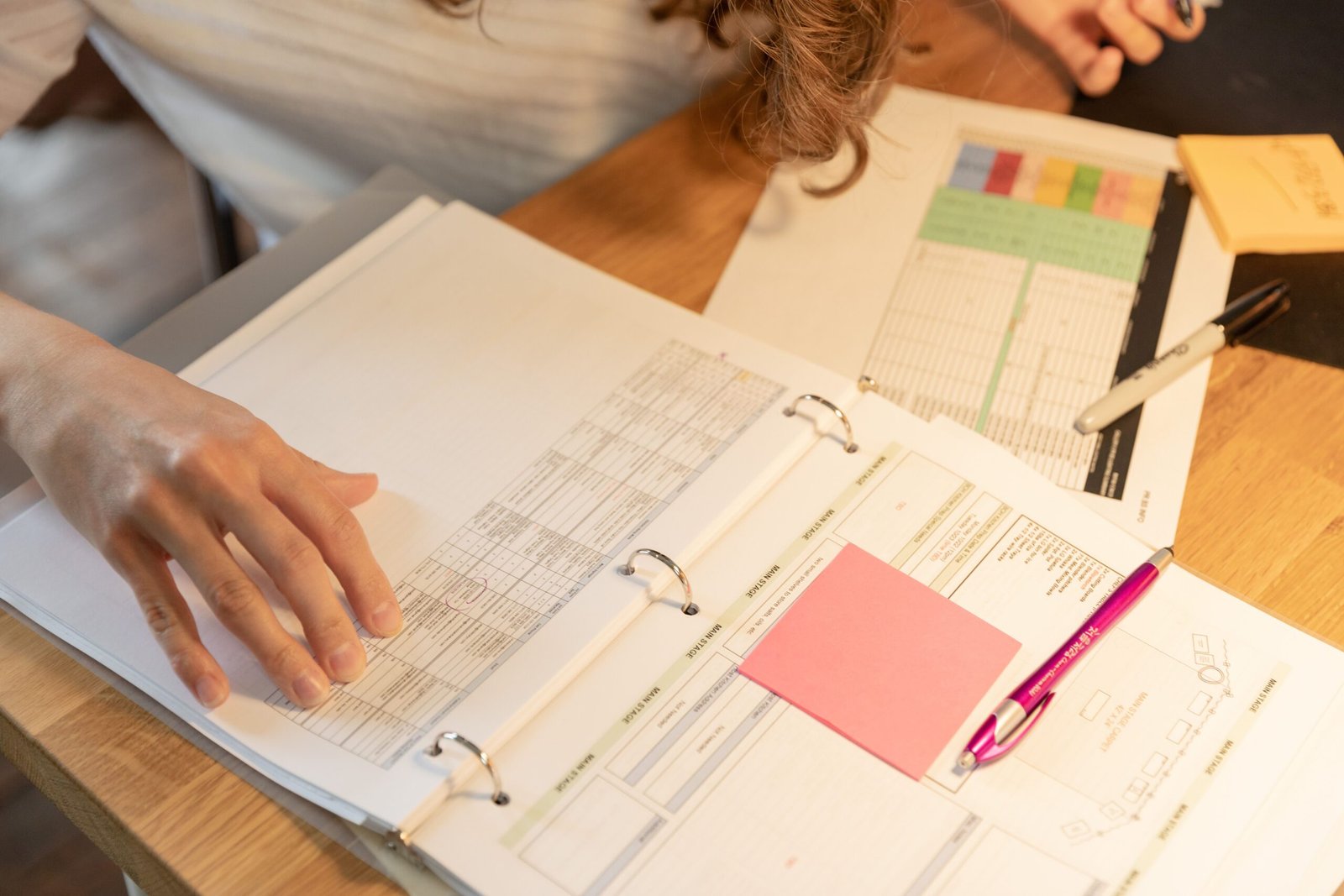 Person reviewing documents with sticky notes on a desk, representing writing an employee handbook