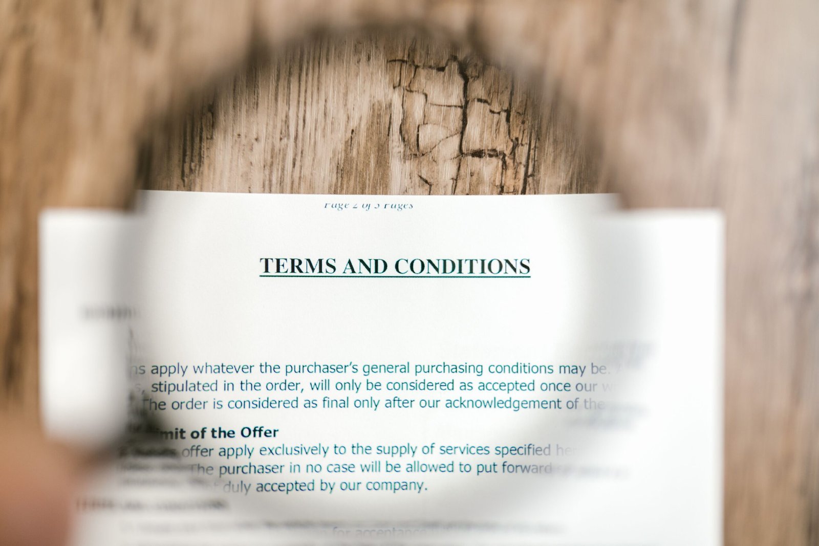 Terms and conditions document viewed through a magnifying glass, representing key clauses in a supplier contract
